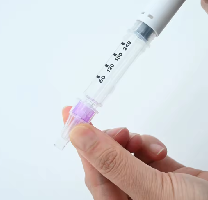 Cartucho de la pluma de insulina con conjunto de aguja púrpura acoplado, junto al cuerpo blanco